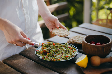 Woman's hands putting guacamole on a toast with a fork. Summer picnic with Mexican food