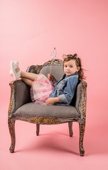 Obraz premium young girl in a chair with a stick. On pink background with copy space