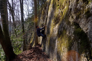Young man bouldering on a rock in the forest in the evening © Thomas