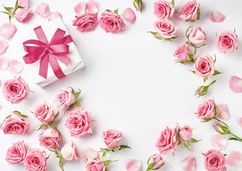 Fototapeta na wymiar Rose flowers and gift on white background with copy space for design, text. Top view of pink roses and rosebuds. Happy Mothers Day.