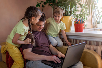 Happy man with children using laptop and earphone during his home working, life in quarantine