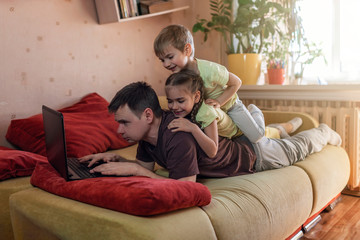Happy man with children using laptop and earphone during his home working, life in quarantine