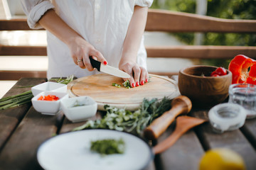 Obraz na płótnie Canvas Woman's hands chopping green onions on a wooden plate. Making guacamole
