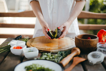 Woman's hands cutting avocado in half. Two avocado halves ready for guacamole making