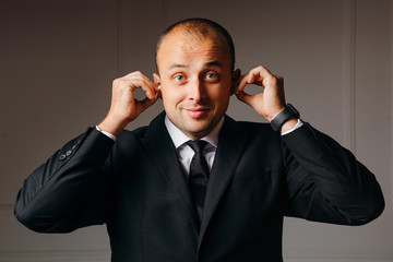 Happy businessman looking at camera while listening music in earphones