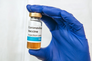 the doctor is holding a test tube with a coronavirus vaccine on a white background. Vaccine covid-19. Pandemic 2020. The doctor's hands are in blue medical gloves. A cure for the virus.