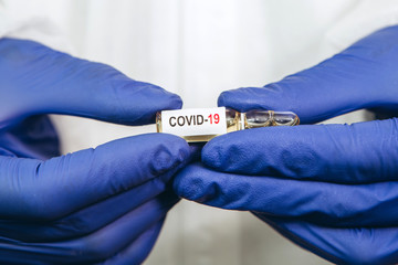 the doctor is holding a test tube with a coronavirus vaccine on a white background. Vaccine...