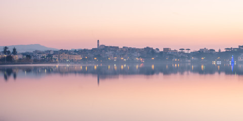 skyline all'alba di un paese italiano con riflessi sul lago
