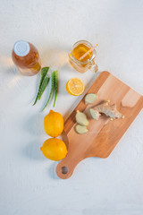 Kombucha in a bottle, lemon, sliced ginger on a light background. Top view.