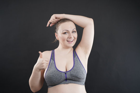 young happy plus size caucasian woman shows her unshaved armpit