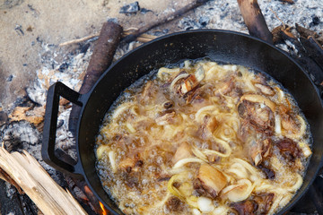 Pieces of lamb with onion are fried in boiling oil on the fire. As a stage in the preparation of traditional pilaf.