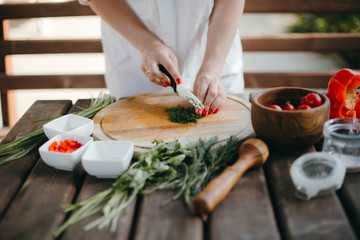 Woman's hands chopping dill on a wooden plate. Making guacamole