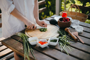 Woman's hands chopping parsley on a wooden plate. Making guacamole