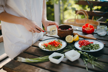 Woman's hands adding chopped garlic, cooking guacamole. Picnic summer cooking.