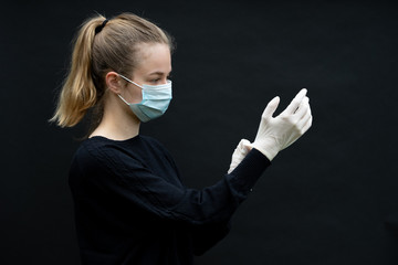 une jeune femme portant un masque de protection enfile des gants de protection