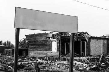 Black and white photo of an empty plaque standing in front of the ruins and ruins of an old house in Northern Russia in Yakutia.