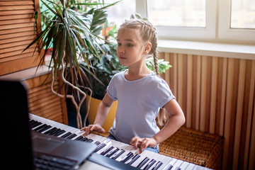 Young musician playing classic digital piano at home during online class at home, self-isolation