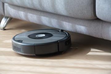 Fototapeta na wymiar robot vacuum cleaner under a sofa.