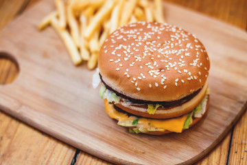 Fast food set big hamburger and french fries on wood background