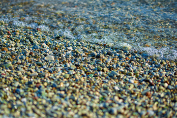 Colorful sea pebbles in a wave on the beach