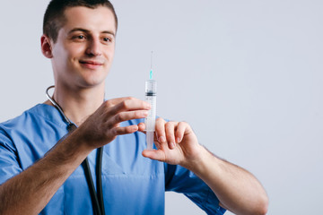 Portrait of young doctor intern holding syringe for injection isolated on white background