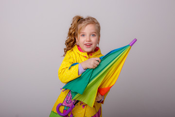 baby girl with bright umbrellas in boots on a gray background, spring