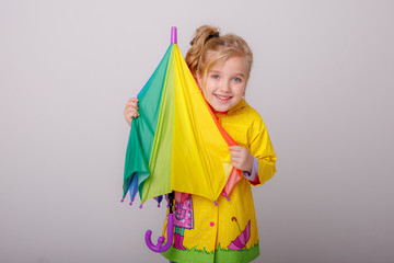 baby girl with bright umbrellas in boots on a gray background, spring
