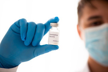 Vaccine bottle in male hand close up, doctor in medical mask. Concept of vaccination, Covid-19...