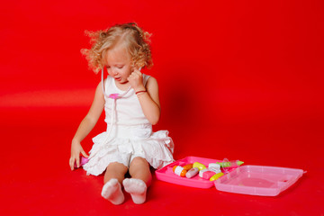 Adorable smiling little girl playing at the doctor listening toy stethoscope isolated on red