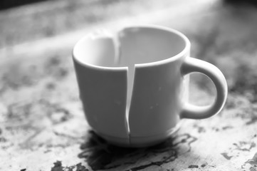 Black and white image of a broken mug on a stained surface