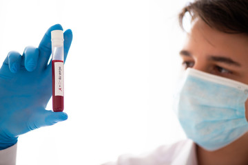 Test tube in male hand, doctor in medical mask holding vial with red liquid. Concept blood sample,...