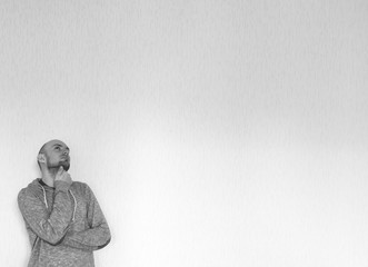 Male person with hoodie is thinking and looking up. Black and white background image. Concept of dreaming man.