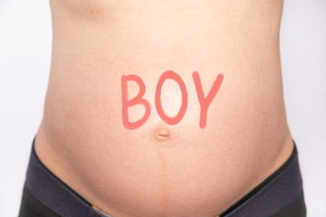 Belly of a pregnant woman with the words "boy"