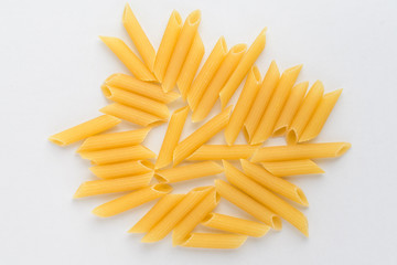 Dried penne Italian pasta in a round bowl ready to be cooked, isolated on white table, top view or flat lay of healthy food 