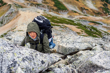 Lady Is Climbing Up To The Rocks with Backpack