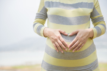 Close up of pregnant women smile Holding the stomach, hand-made in heart shape