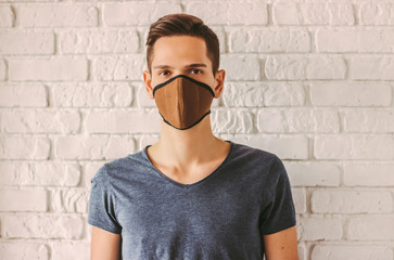 Young man in protective face mask as preventive measure from chinese coronavirus COVID-19. Hipster...