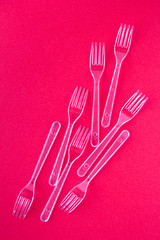 White disposable forks on pink background close-up - Environmental problem concept