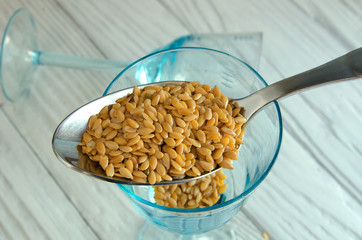 Flax seeds on the background of old cutlery and glass goblets.