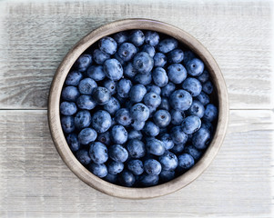 Blueberries in a wooden bowl on a wooden table. Bowl with berries.