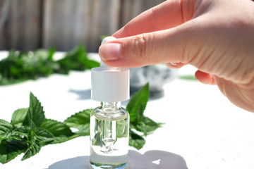 Alternative medicine, a bottle of serum and a pipette in the hands of a girl. On a natural background.