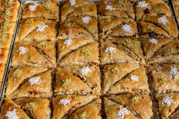 Close up of traditional oriental sweet pastry cookies known as backlava, Turkish desert with sugar, honey, walnuts and pistachio, in display at an weekend street food market, top view, soft focus