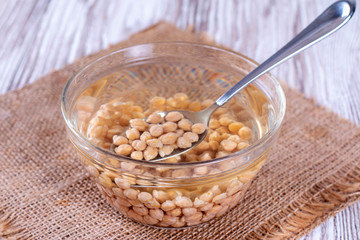 Chickpeas in water in glass bowl with a spoon
