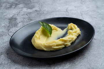 Side dish: mashed potato on black plate decorated with basil