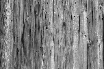 Wall of vertical wooden weathered planks in black and white.