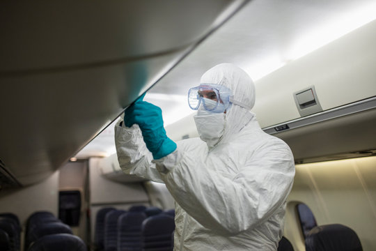 Worker in clean suit sanitizing airplane during COVID-19 pandemic