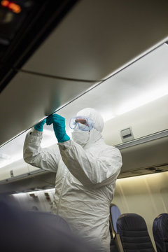 Worker in clean suit disinfecting airplane during COVID-19 pandemic