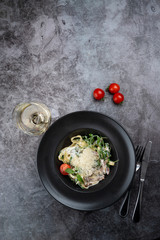 Tyrolean ham pasta with arugula and a glass of good white wine, vertical copy space