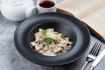 Farfalle with beef and sun-dried tomatoes on grey stone background