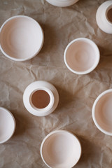 dishes made of white clay without glaze after firing on a brown background close-up. pottery top view